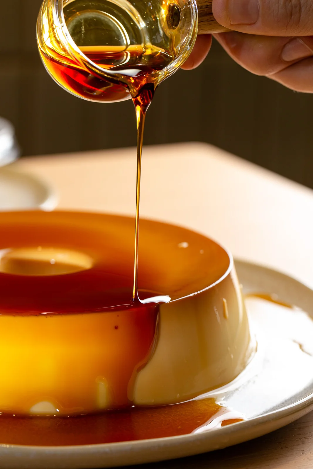 Calda de caramelo sendo servida sobre um pudim